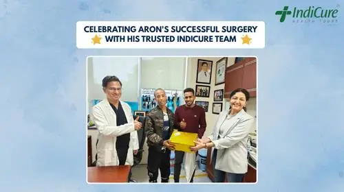 Aron and his family posing with the IndiCure team post-surgery. They are celebrating his successful surgery, and Aron is holding a gift box.